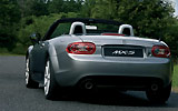 Mazda MX-5. Modelo 2009. Imagen. Lateral- posterior. Coche parado. Descapotado. Carretera. Gris.
