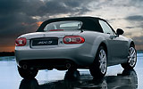 Mazda MX-5. Modelo 2009. Imagen. Posterior- lateral. Coche parado. Techo de lona. Carretera. Gris.