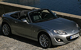 Mazda MX-5. Soft Top. Modelo 2009. Imagen exterior. Frontal cenital lateral. Coche parado. Carretera. Gris.