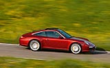 Porsche 911 Targa. Modelo 2009. Imagen. Lateral. Luna trasera de vidrio abatible. Coche en movimiento. Carretera. Rojo rub� metalizado. 