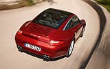 Porsche 911 Targa. Modelo 2009. Imagen. Posterior- lateral. Techo acristalado. Coche en movimiento. Carretera. Rojo rub� metalizado. 